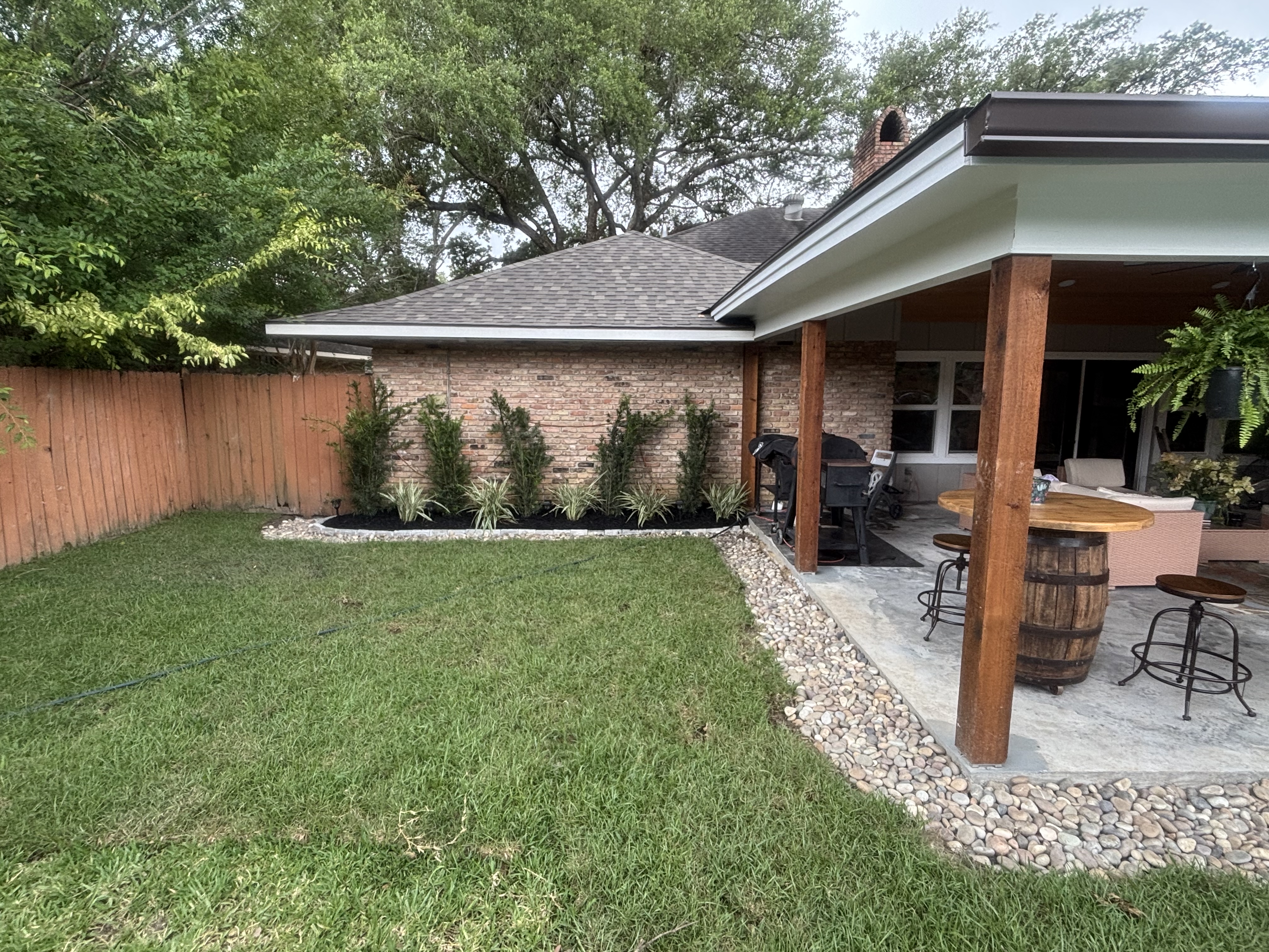 After - complete backyard landscape renovation with sod, shrubs, mulch beds, and covered patio in Baton Rouge