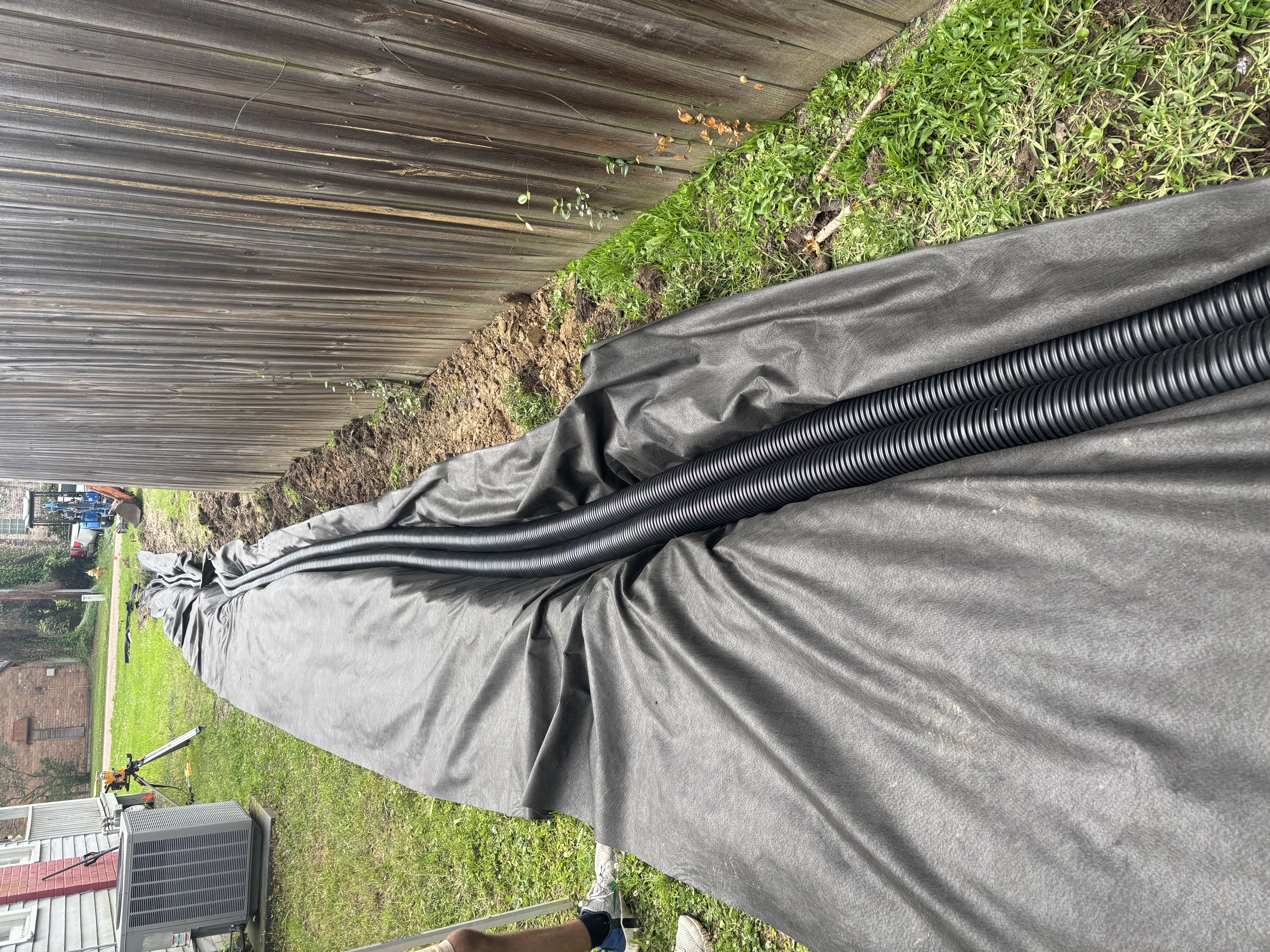 Twin corrugated pipes in fabric-lined French drain trench - Baton Rouge drainage installation