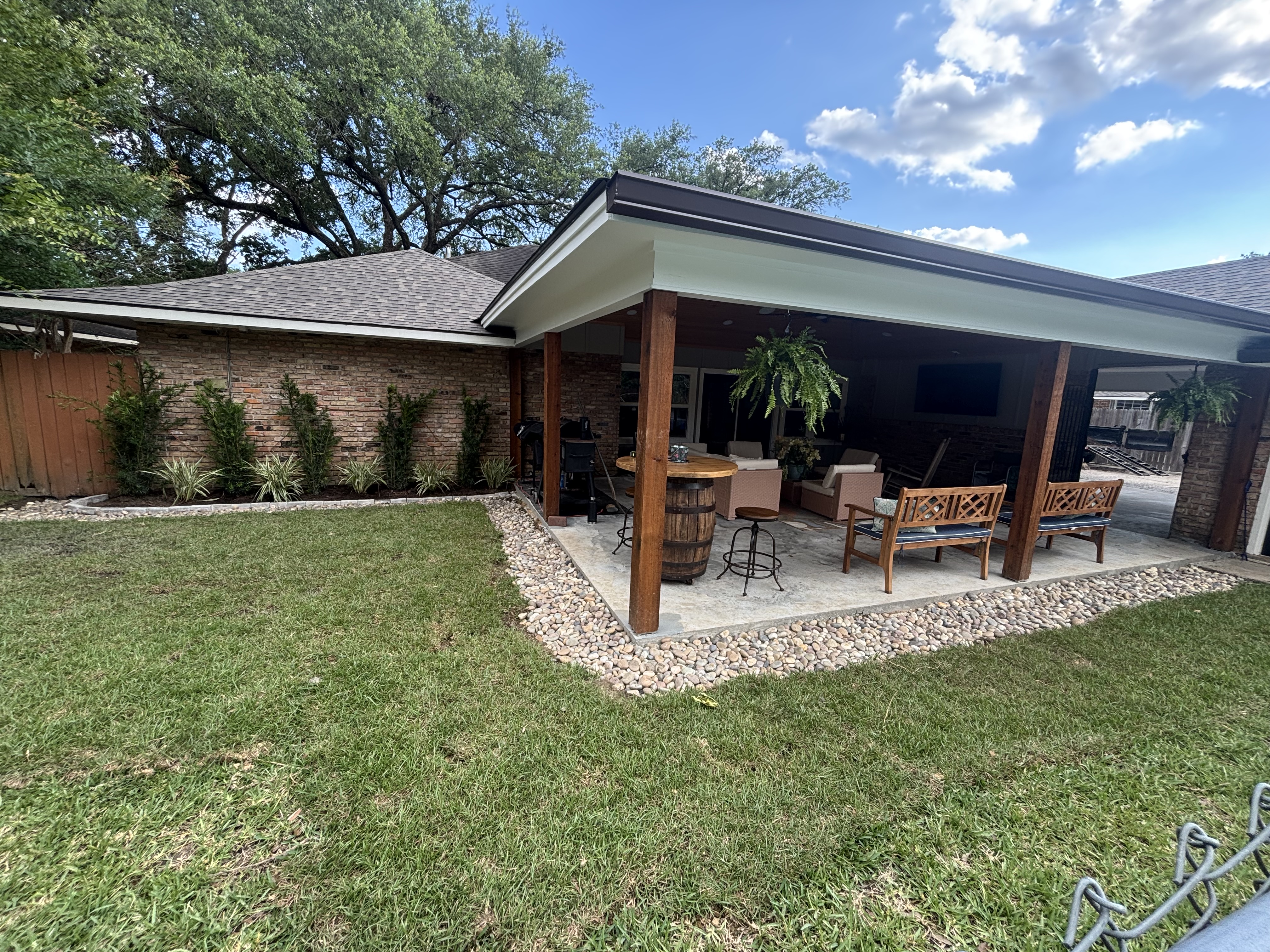 Open French drain with decorative beach pebble border around covered patio - Baton Rouge drainage