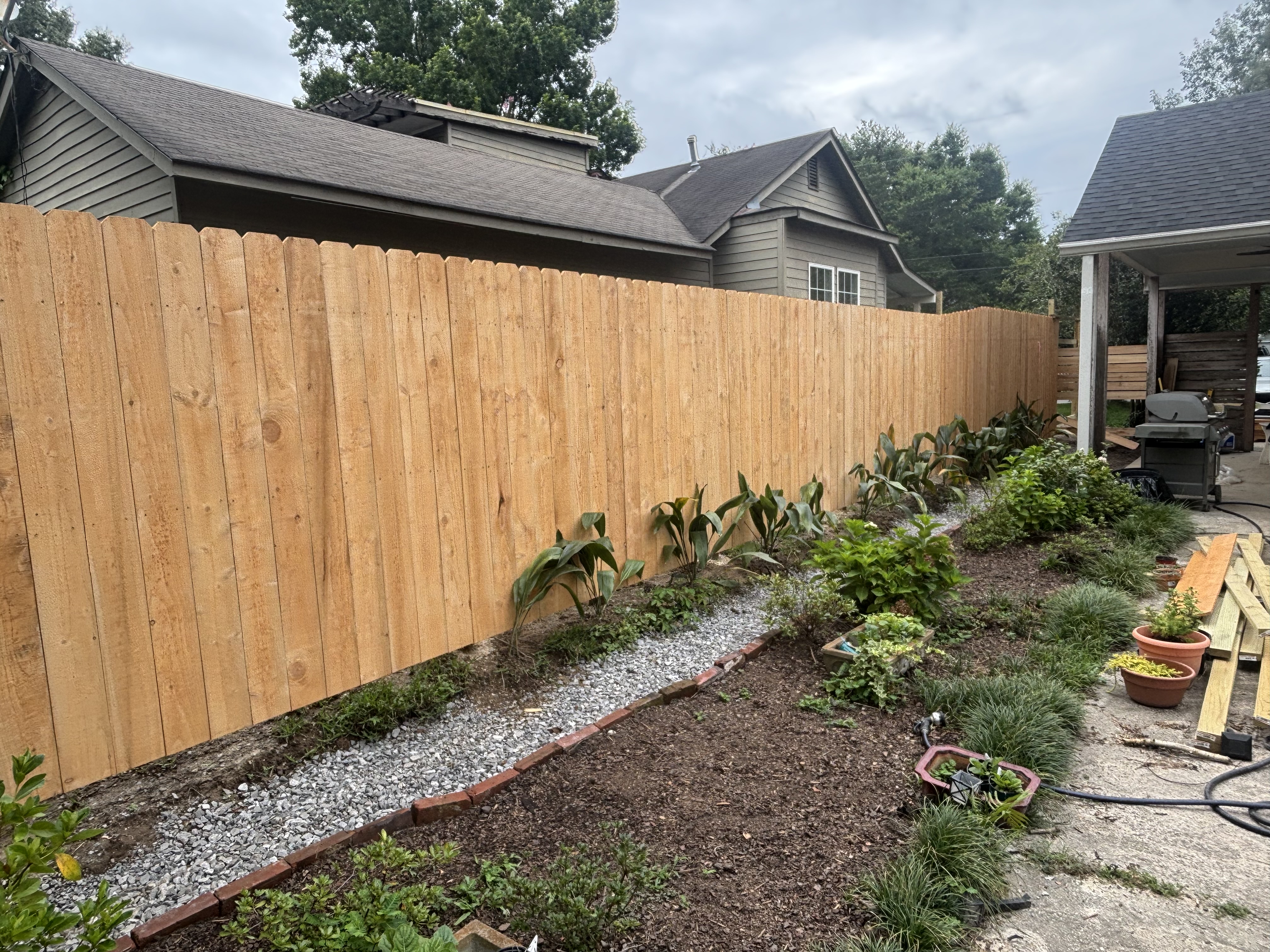 Finished open French drain with brick border, new cedar fence, and landscape plantings - Baton Rouge drainage