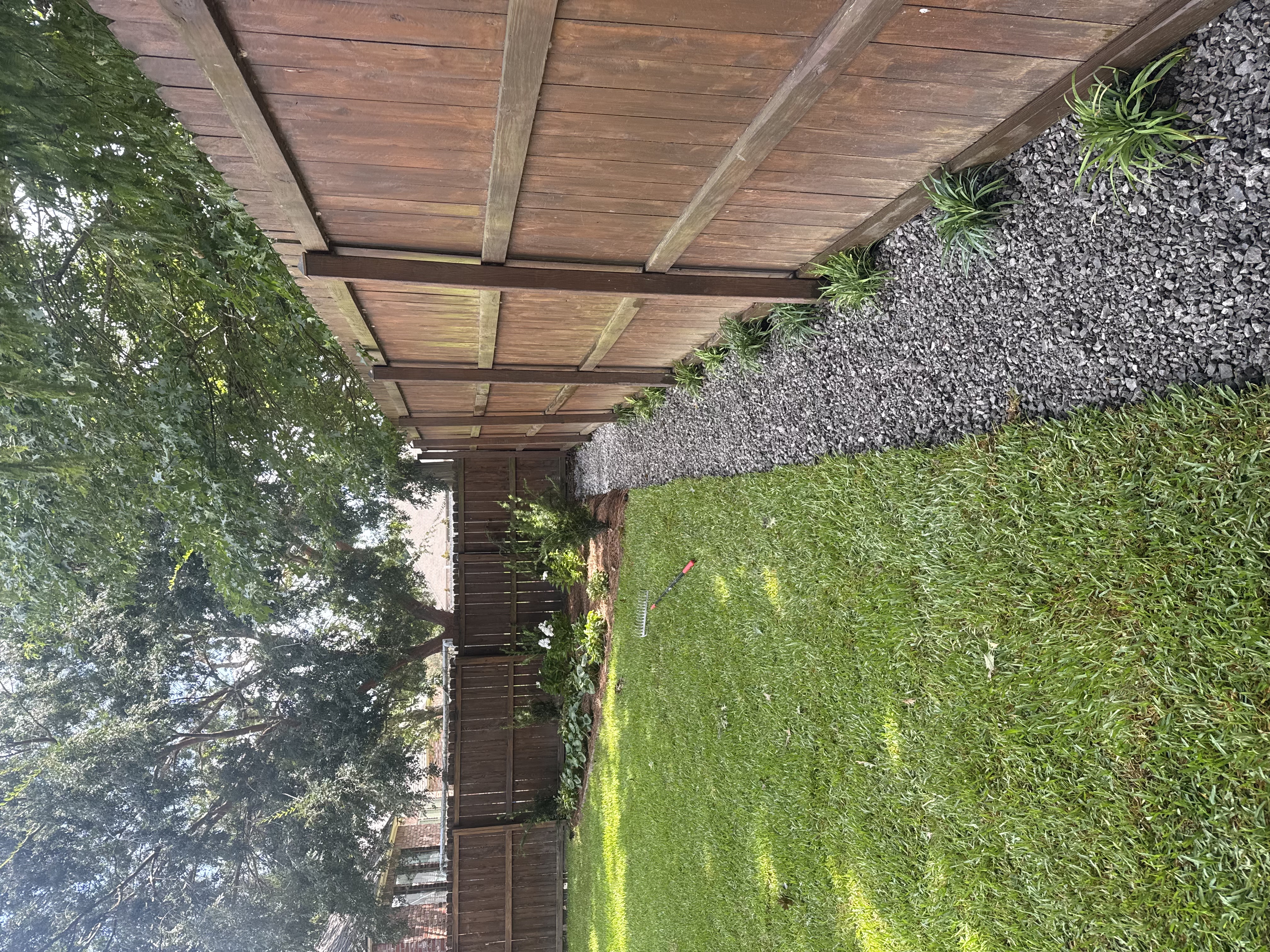 Open French drain gravel channel along fence line with liriope plantings and new sod - Baton Rouge visible drainage design
