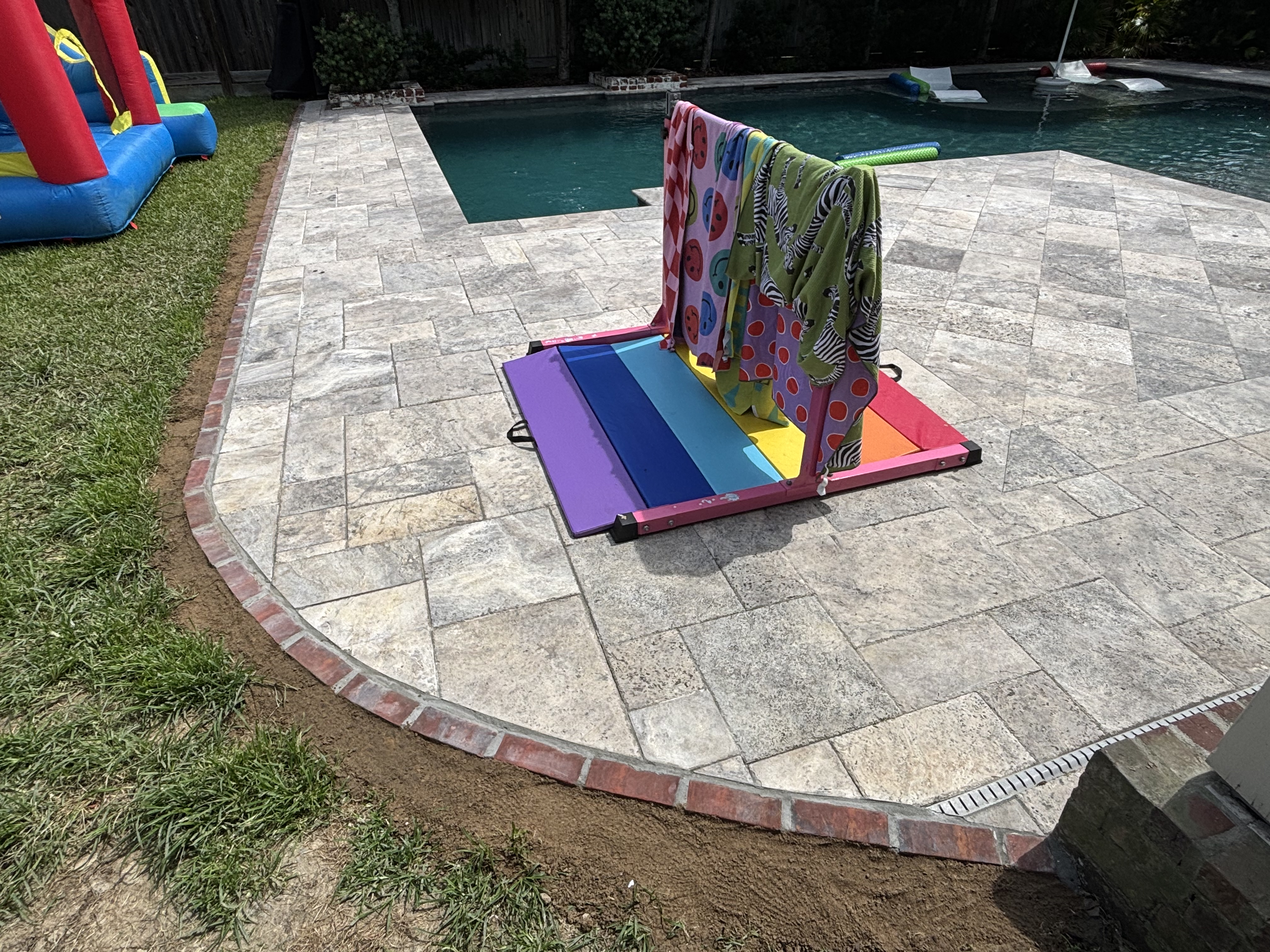 Travertine pool deck with brick rowlock border and channel drain - Baton Rouge masonry